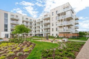 un immeuble d'appartements avec un jardin en face dans l'établissement Downtown Apartments Seaside Mila Baltica - Sauna, Gym & Parking, à Gdańsk