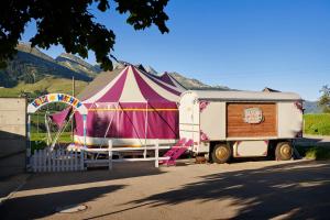 uma tenda de circo e um reboque num parque de estacionamento em Reka-Feriendorf Wildhaus em Wildhaus