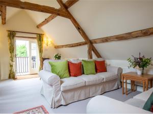 a living room with a white couch with green and red pillows at Hayloft at NewBarn Farm in Chipping Norton