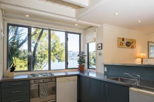 a kitchen with blue cabinets and a large window at Bruce Waterfront Apartments in Akaroa