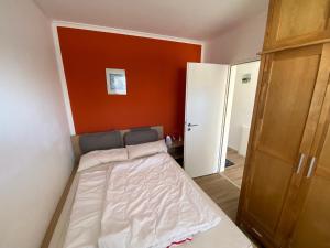 a small bed in a room with an orange wall at Entspann you in Wangerland