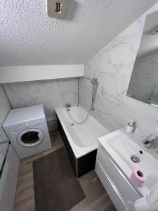 a white bathroom with a sink and a washing machine at les cristallines in Le Lioran