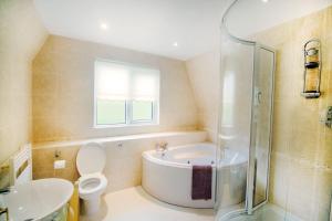 y baño con bañera, aseo y lavamanos. en Lodges in Lanivet Cornwall with indoor pool, en Bodmin