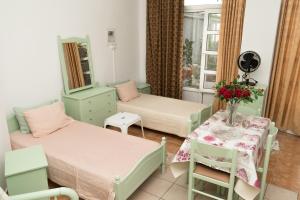 una camera con due letti e un tavolo con fiori di STAVROS Studio Apartment in kos town a Città di Kos