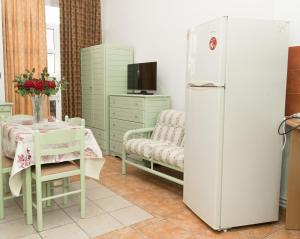 a kitchen with a white refrigerator and a table with a chair at STAVROS Studio Apartment in kos town in Kos Town