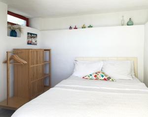 a bedroom with a white bed and a wooden shelf at Mykonos Love Nest in Ano Mera