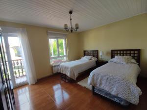 a bedroom with two beds and two windows at Casa Rural La Rasilla in Castillo-Pedroso