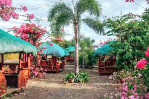 einen Garten mit Stühlen, einer Palme und Blumen in der Unterkunft Airport View Hotel in Vigan City