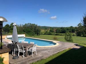 - une table avec un parasol à côté de la piscine dans l'établissement La Grenaderie, à Sergeac