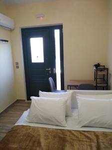 Habitación con cama con almohadas blancas y puerta negra. en Serafi Cozy Rooms en Archangelos