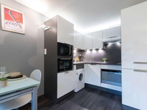 a kitchen with white cabinets and a washer and dryer at Appartement Saint-Lary-Soulan, 2 pièces, 4 personnes - FR-1-296-241 in Saint-Lary-Soulan