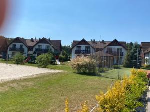 a group of houses in a yard with a playground at Apartament szafirowy z basenem koło Łeby in Żarnowska