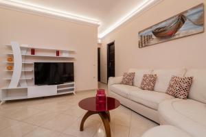 a living room with a white couch and a tv at Taso's Modern House! in Zakynthos Town