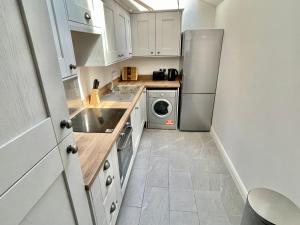 a kitchen with white cabinets and a stainless steel refrigerator at The Old Post Office - central Helmsley with parking in Helmsley