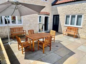 a wooden table and chairs with an umbrella on a patio at Rye Court Cottage - Stunning cottage in central Helmsley with parking in Helmsley