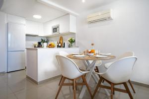 a kitchen with a table and white chairs in a kitchen at Villa Maya by Maspalomas Holiday Villas in Pasito Blanco
