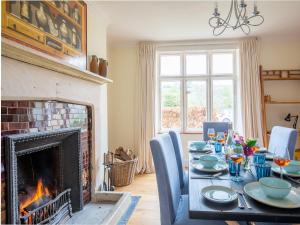a dining room with a fireplace and a table and chairs at Lake Cottage in Woodchester