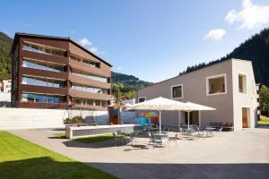 ein Gebäude mit Stühlen, Tischen und Sonnenschirmen in der Unterkunft Reka-Feriendorf Blatten-Belalp in Blatten bei Naters