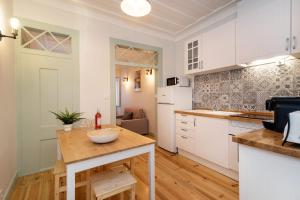 リスボンにあるGuestReady - Cosy Madalena Flatの白いキャビネットと木製テーブル付きのキッチン