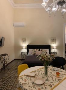 ein Schlafzimmer mit einem Bett und einem Tisch mit Blumen in der Unterkunft Lex Suites in Catania