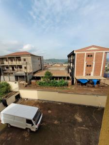 a white van parked in a parking lot with buildings at Hôtel Altitel in Bafoussam