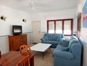 a living room with two blue couches and a table at Beachfront House sea views near historic Cartagena in Cartagena