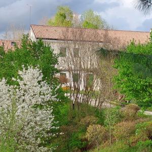 un vieux bâtiment avec des arbres et des fleurs blanches dans l'établissement Agriturismo l'Eremo, à Volpago del Montello