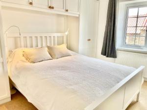 a white bed in a white bedroom with a window at The Annex - central Helmsley with parking in Helmsley