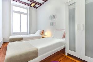 リスボンにあるLisbon Boulevardの白い部屋で、ベッド2台、窓が備わります。