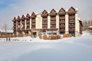 un gran edificio con nieve delante en Reka-Feriendorf Sörenberg, en Sörenberg