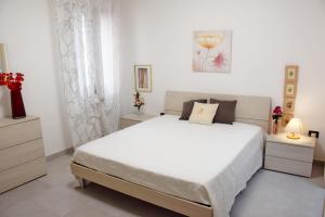 a white bedroom with a large bed and two night stands at Toto Residence in Torre Lapillo