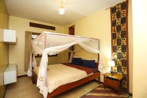 una camera con letto a baldacchino di Remarkable 2-Bed Cottage Along Gayaza road a Kampala