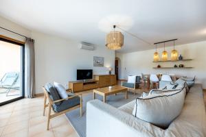 a living room with a couch and chairs and a tv at Aum Praia da Luz Resort Apartment in Luz