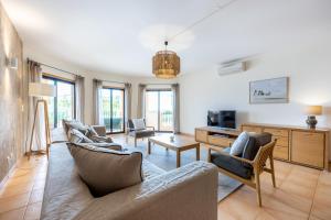 ein Wohnzimmer mit einem Sofa, Stühlen und einem TV in der Unterkunft Aum Praia da Luz Resort Apartment in Luz