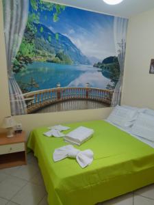 a bedroom with a green bed with a view of a lake at SummerAndros Apartment in Andros