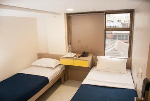 ムンバイにあるCity Hotelのベッド2台、電話が備わる小さな客室です。