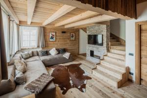 a living room with a couch and a stone fireplace at Chalet Socrepes - Dolomiti Skyline in Cortina dʼAmpezzo