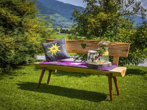 drewniana ławka z poduszkami w trawie w obiekcie Holiday Home Erlachhof by Interhome w mieście Niedernsill