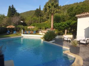 a swimming pool in a yard with chairs and umbrellas at La Villa d'Olivène in Cuers