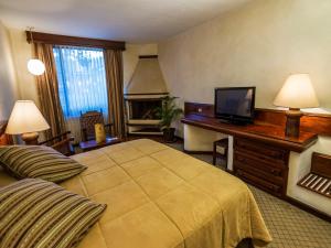 a hotel room with a bed and a television at Hotel Soleil La Antigua in Antigua Guatemala