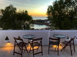 a table and chairs on a balcony with a sunset at Mama's Pension in Agios Stefanos