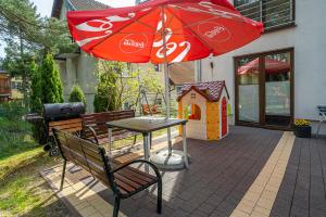 a patio with a table and an umbrella and a play house at Willa Magda in Jastrzębia Góra