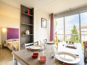 a dining room with a table and a bedroom at Apartment Terrasses de la Baronnie-3 by Interhome in Le Grau-du-Roi