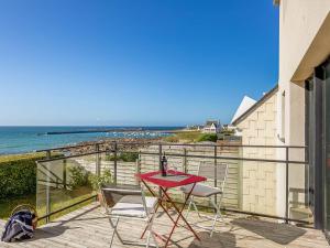 einen roten Tisch und Stühle auf einem Balkon mit Meerblick in der Unterkunft Holiday Home La Villa Marine - PLC225 by Interhome in Plouescat