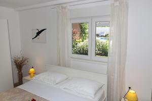 a white bedroom with a bed and a window at Vila Anda in Zadar