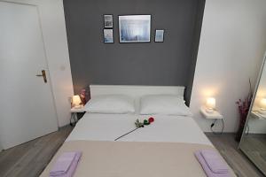 a bedroom with a white bed with a flower on it at Vila Anda in Zadar