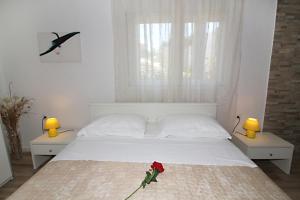 a bedroom with a white bed with a red rose on it at Vila Anda in Zadar