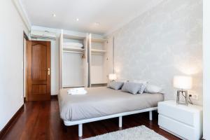 1 dormitorio con cama blanca y estanterías blancas en Beach and Chill apartment by Cisan Rentals en San Sebastián