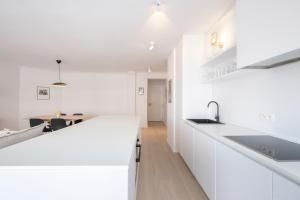 a white kitchen with white counters and a table at Trendy 1 bedroom flat near Schuman and Berlaymont in Brussels
