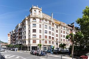 un gran edificio en una calle de la ciudad con motocicletas aparcadas delante en Beach and Chill apartment by Cisan Rentals, en San Sebastián